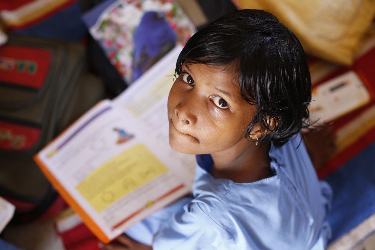 A young girl looking up from an open school book